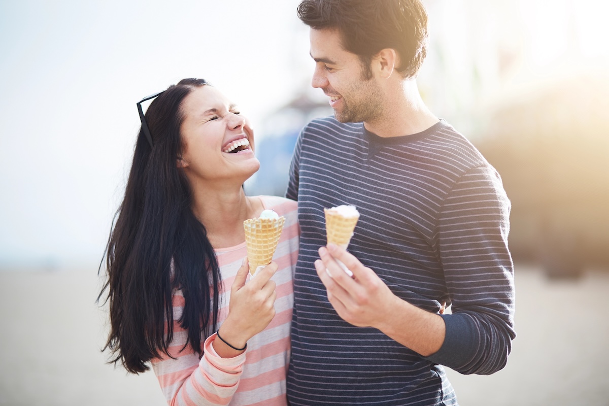 arm-in-arm couple outdoors walking and sharing ice creams