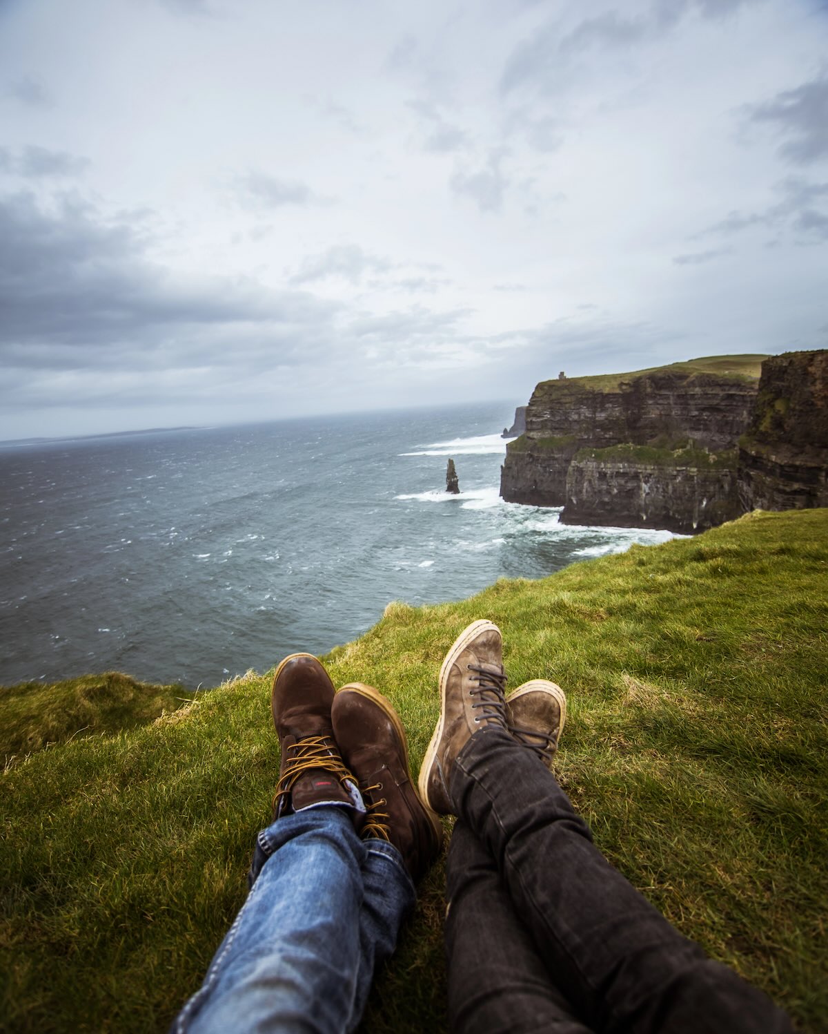 Couple laying on the edge of an Irish cliff