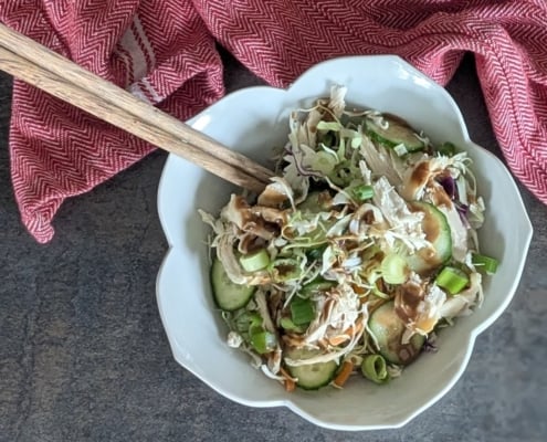 closeup of a rotisserie chicken rice bowl with a pair of chopsticks and a red and white cloth napkin