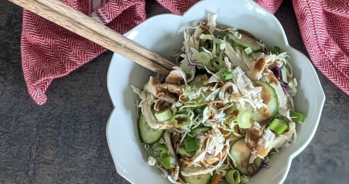 closeup of a rotisserie chicken rice bowl with a pair of chopsticks and a red and white cloth napkin