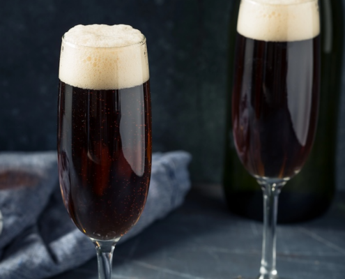 two champagne flutes of black velvet Irish Champagne cocktails on a dark gray background