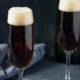 two champagne flutes of black velvet Irish Champagne cocktails on a dark gray background