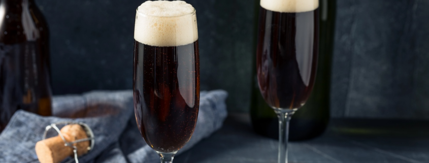 two champagne flutes of black velvet Irish Champagne cocktails on a dark gray background