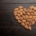 A closeup of roasted almonds in the shape of a heart on a black background