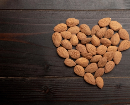 A closeup of roasted almonds in the shape of a heart on a black background