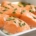 Closeup of poached Atlantic salmon filets topped with Irish butter sauce and parsley flakes in a white dish