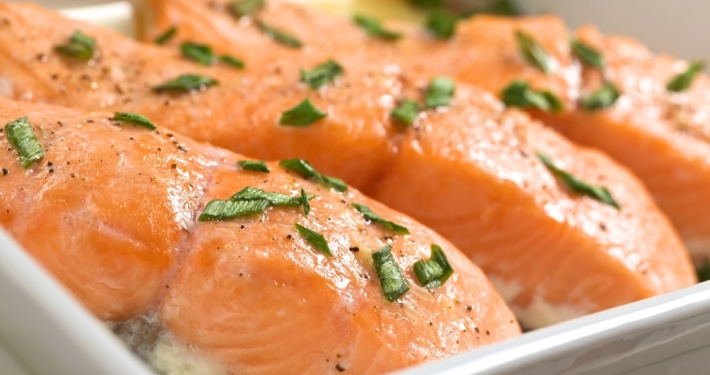 Date Night Atlantic Salmon with Irish Butter Sauce 1 Closeup of poached Atlantic salmon filets topped with Irish butter sauce and parsley flakes in a white dish