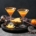 two apple pie martinis on a black background surrounded by tiny pumpkins and cocktail making supplies