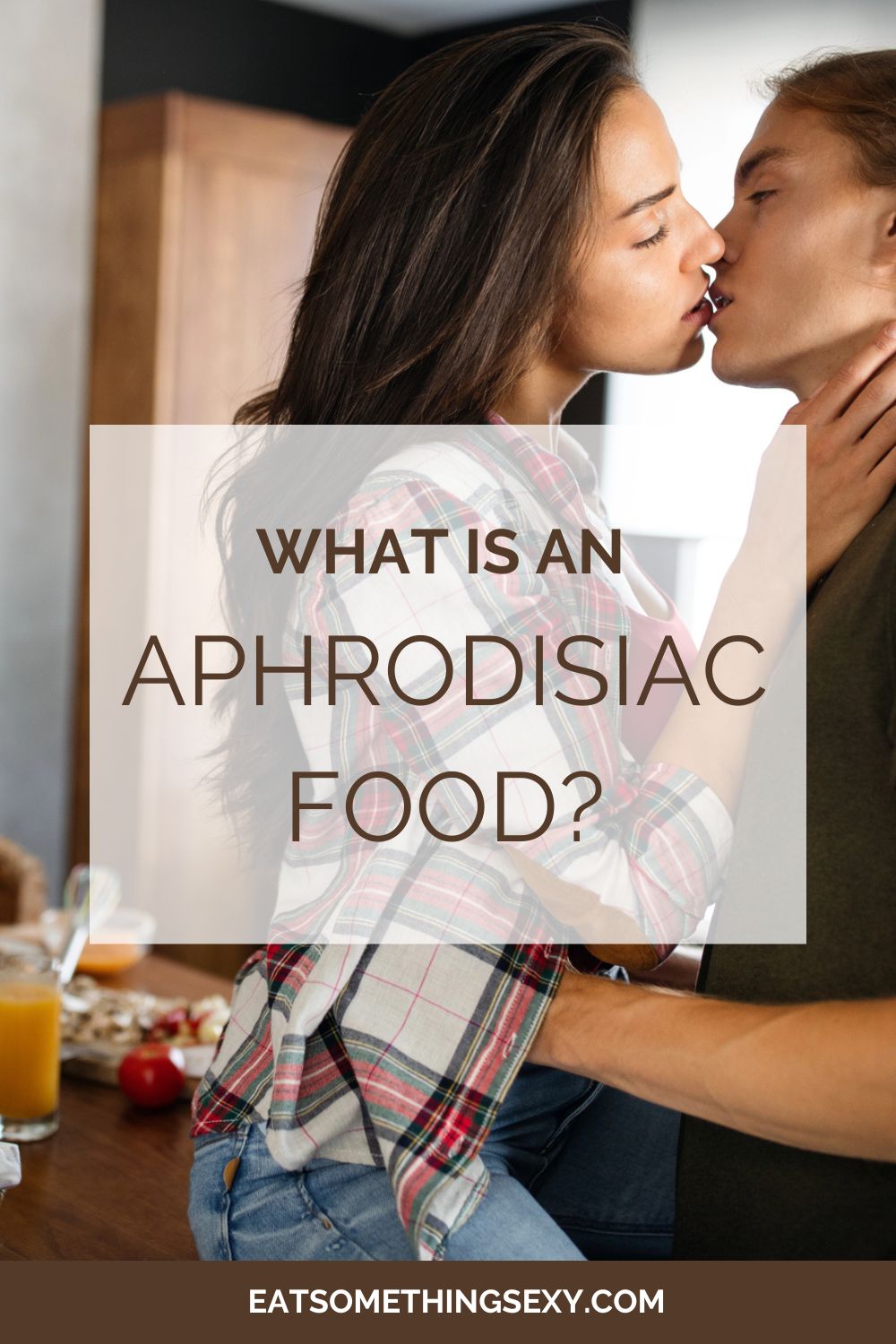 What is an Aphrodisiac Food? 2 Graphic with the text, "What is an aphrodisiac food?" overlayed on an image of a young, mixed-race couple kissing at a kitchen counter laden with dishes of food