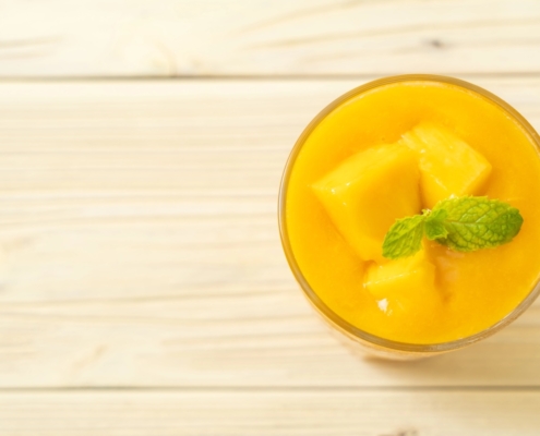 Mango nice cream in a glass dish with chunks of ripe mango and a mint sprig garnish