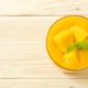 Mango nice cream in a glass dish with chunks of ripe mango and a mint sprig garnish